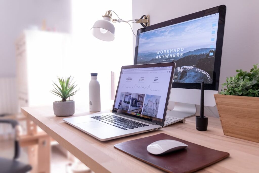 un ordinateur portable est posé sur un bureau d'angle en bois